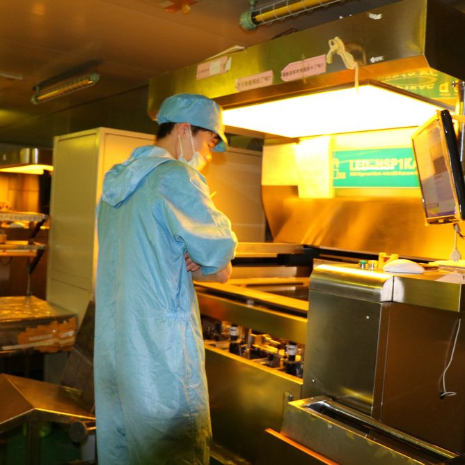 A worker in a cleanroom gown reviewing a job at a machine workstation
